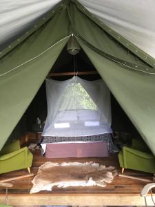 a bed in a green tent with a window at Kaniere Tailings in Hokitika