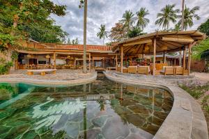 un complejo con piscina y patio con mesas y sillas en Kuda Laut Boutique Dive Resort, en Bunaken