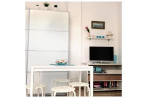 a white table and stools in a room with a tv at Babe beach Apartment in Novalja