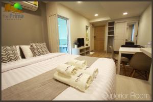 a hotel room with two beds with towels on them at The Prima Residence - SHA Certificate in Bangkok