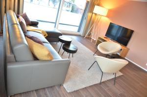 Apartment Narzisse - GriwaRent AG في إنترلاكن: غرفة معيشة مع أريكة وتلفزيون