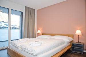 Schlafzimmer mit einem großen weißen Bett und einem Fenster in der Unterkunft Apartment Narzisse - GriwaRent AG in Interlaken