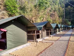 a row of green tents sitting next to a mountain at Jungle Stays in Chail