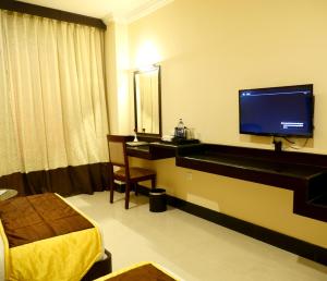 Habitación de hotel con TV, cama y escritorio. en AVS Imperiaa Karaikal, en Karaikal