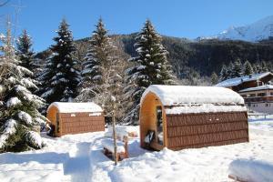 un par de pequeños edificios en la nieve en Presanella Mountain Lodge, en Temù