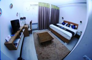 a view of a bedroom with a bed and a television at Rohat Hotel in Dushanbe