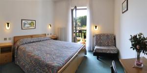 1 dormitorio con 1 cama, 1 silla y 1 ventana en Hotel Italia, en Baselga di Pinè