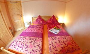 Am Sonnenhang في ايمنستادت ام الغو: غرفة نوم مع سرير بملاءات وردية وأرجوانية