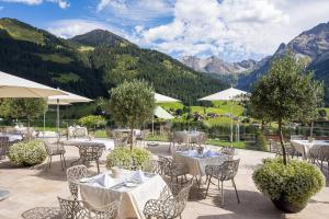 a restaurant with tables and chairs with mountains in the background at Haller's Geniesserhotel in Mittelberg