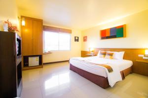 una camera d'albergo con un grande letto e una TV di The Lephant Hotel a Suratthani