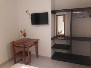 Habitación con mesa y TV en la pared. en Amazon Green Hotel en Iquitos