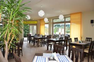 restauracja z drewnianymi stołami i krzesłami oraz oknami w obiekcie Pensjonat i Restauracja Laguna w Pogorzelicy