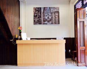 a desk with a picture of a statue on the wall at Jitra Resort in Sukhothai