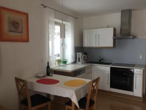 eine Küche mit einem Tisch und eine Küche mit weißen Schränken in der Unterkunft Ferienwohnung Kalin in Neualbenreuth