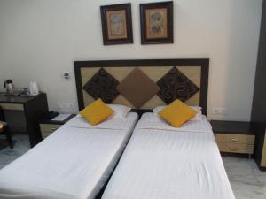 1 dormitorio con 2 camas con almohadas amarillas en East End Retreat, en Nueva Delhi