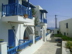 una fila de edificios blancos con balcones azules y el océano en La Fontana en Naxos