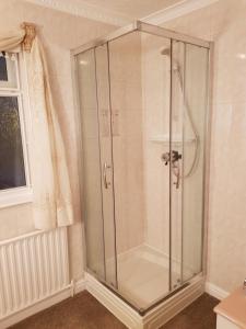 a glass shower stall in a bathroom with a window at Glenkerry in Ingoldmells