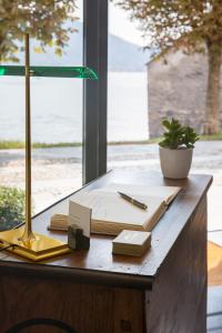 un escritorio con una lámpara y libros. en Villa Maria Hotel en Cannobio