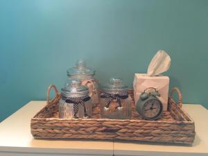 a basket with glass jars and an alarm clock on a table at Le Verger B&B in Gorron