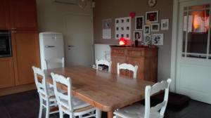 una cucina con tavolo in legno e sedie bianche di B&B De Laak a Bilzen