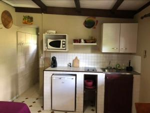 een kleine keuken met een koelkast en een magnetron bij Le bungalow des bougainvilliers in Ducos