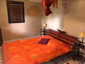 een slaapkamer met een groot bed en een oranje deken bij Le bungalow des bougainvilliers in Ducos