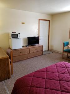 a room with a bed and a tv on a dresser at Home Motel Abbotsford in Abbotsford