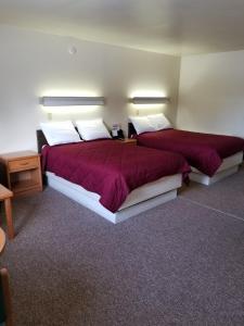 two beds in a room with red sheets and pillows at Home Motel Abbotsford in Abbotsford