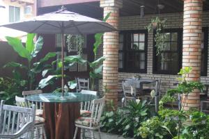 a table and chairs with an umbrella on a patio at Pousada Narinari in Bombinhas