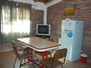 Habitación con mesa, TV y nevera. en Departamentos Calderon en San Rafael