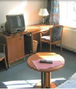 a room with a desk with a tv and a chair at Hotel Haus Marienthal in Zwickau