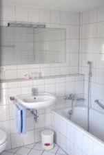 a white bathroom with a sink and a bath tub at Hotel Haus Marienthal in Zwickau