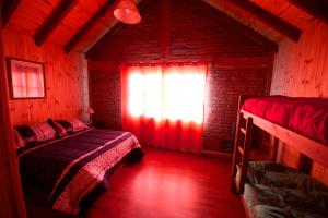 a bedroom with two beds and a window with red light at El hostel secreto in Lago Puelo