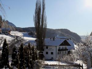 ein weißes Haus im Schnee mit Bäumen in der Unterkunft Gasthof Tschötscherhof in Kastelruth