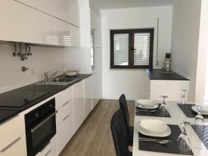 a kitchen with white cabinets and a table with chairs at Casa da Fonte in Foz do Arelho