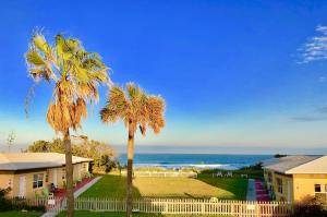 a house with palm trees in front of the ocean at Ocean Front Paradise Resort in Melbourne