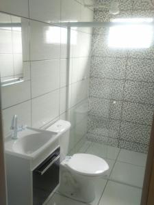 Baño blanco con aseo y lavamanos en Apartamentos C. Santos, en Penha
