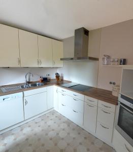 Una cocina con gabinetes blancos y un fregadero. en FeWo Familie Walther, en Markdorf 19 fotos más