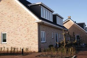 a brick house with a black roof at Duinvilla Aan de Zee B&B in Zoutelande