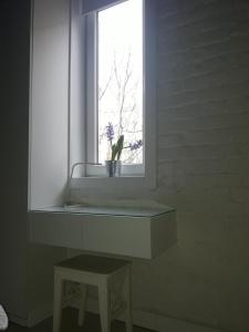 a window with a potted plant on a shelf and a stool at Momo Apartment in Belgrade