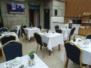 un restaurante con mesas y sillas blancas y una cocina en Hotel Porto Rico, en Oporto