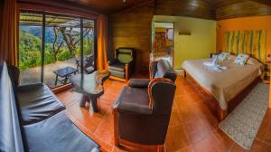 Rainbow Valley Lodge Costa Rica في مونتيفيردي كوستاريكا: غرفة نوم بسرير واريكة وكراسي