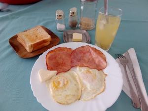 a white plate with eggs ham and bread on a table at Park Hotel in Port-au-Prince