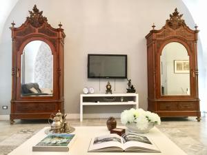 uma sala de estar com televisão e uma mesa com livros em Dimora del Papa em Catânia