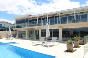 een gebouw met een zwembad en een patio met parasols bij Sybella in Merimbula