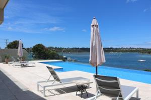 a patio with chairs and an umbrella next to a swimming pool at Sybella in Merimbula