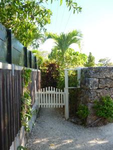 a fence with a white gate and a stone wall at Sapunaya-さぷな家 in Taketomi
