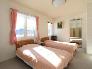 1 dormitorio con 2 camas y ventana en Pension Himawari en Iizuna
