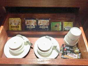 a wooden shelf with two cups and plates and books at New Bale Motel in Bali