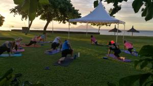 a group of people doing yoga on the grass at Rapopo Plantation Resort in Kokopo
